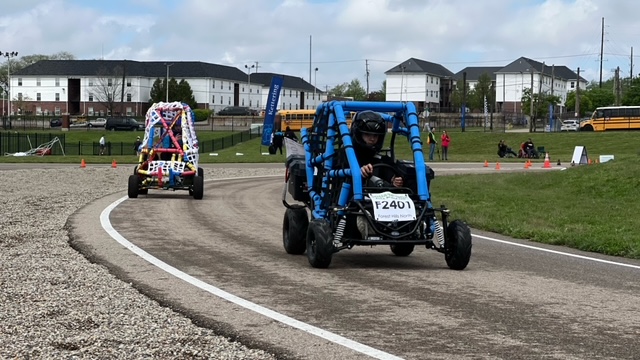Two electric vehicles with the blue vehicle with roll bars in the lead.